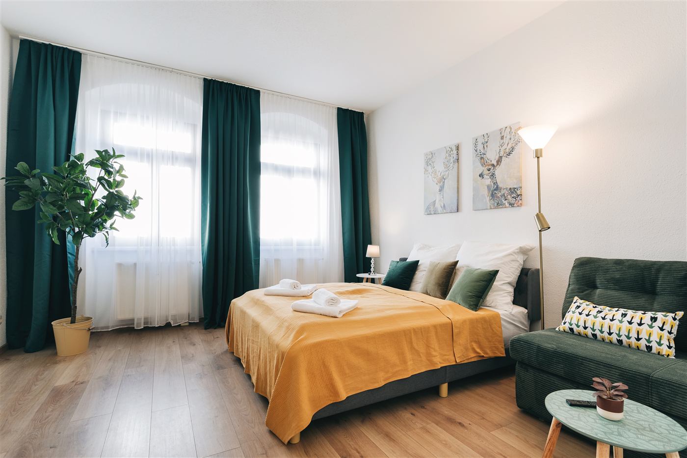 Junior Apartment Meißen Schlafzimmer mit Doppelbett, Sofa und grünen Vorhängen